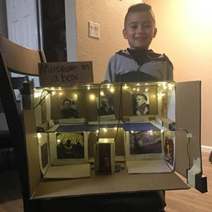 A young child with his family's museum in a box diorama